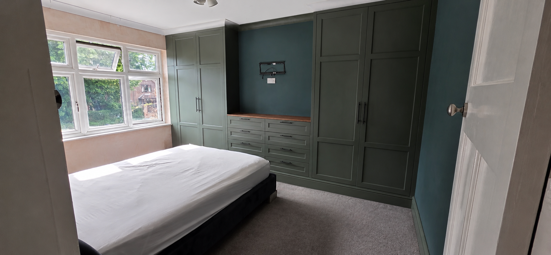 Custom Enclave Cabinetry floor-to-ceiling wardrobes in a rich, muted green